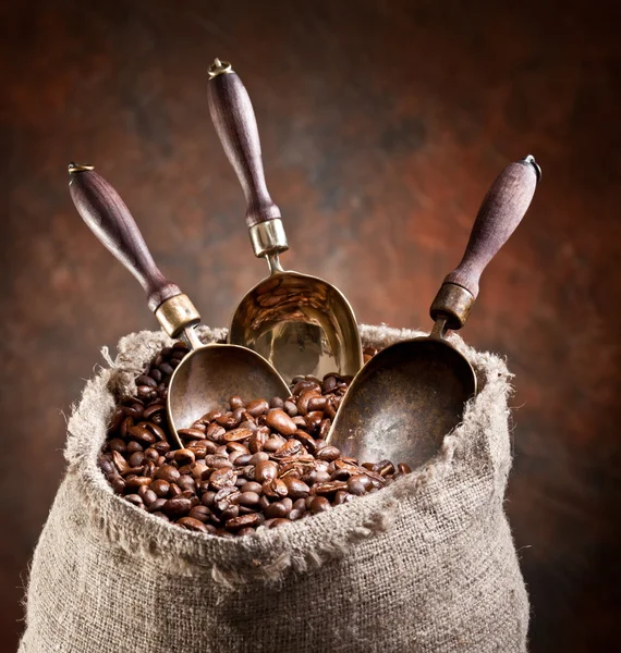 Saco de grãos de café e colher. Em um fundo escuro . — Fotografia de Stock