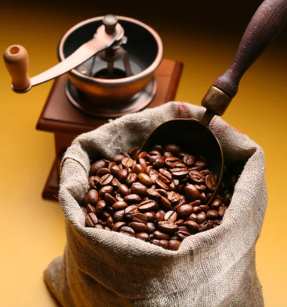 Sack of coffee beans and scoop. On a dark yellow background. — Stock Photo, Image