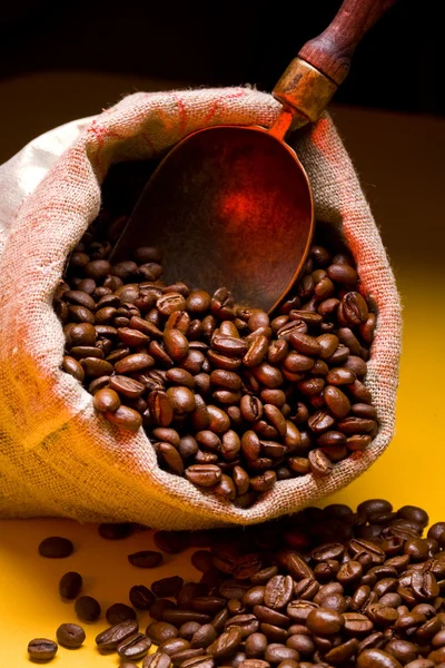 Säck kaffebönor och scoop. på en gul bakgrund. — Stockfoto