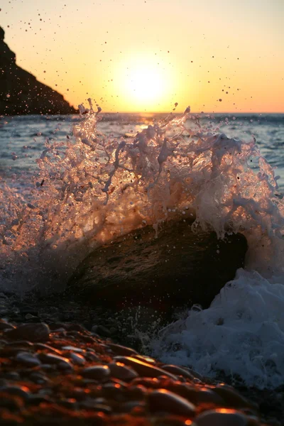 Ao nascer do sol, ondas caem sobre a pedra — Fotografia de Stock