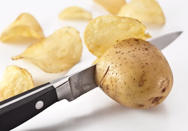 Conceptual image - the knife cuts fresh potatoes and potato chip Stock Picture