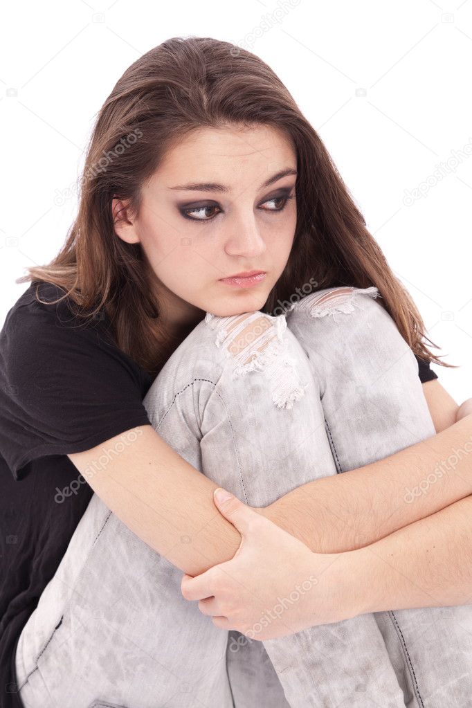 Sad girl teenager sits twining arms about legs
