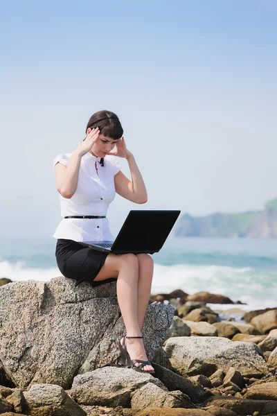 Chica sentada en la playa con un portátil — Foto de Stock