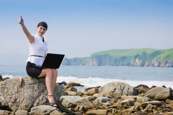 Sweet girl sits on a rocky shore — Stock Photo, Image