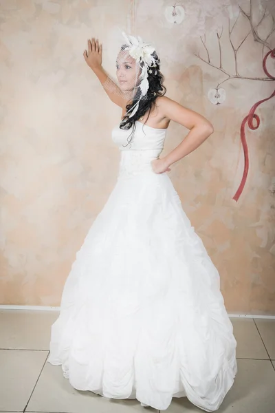 Zwoele bruid staat in een elegante witte jurk — Stockfoto