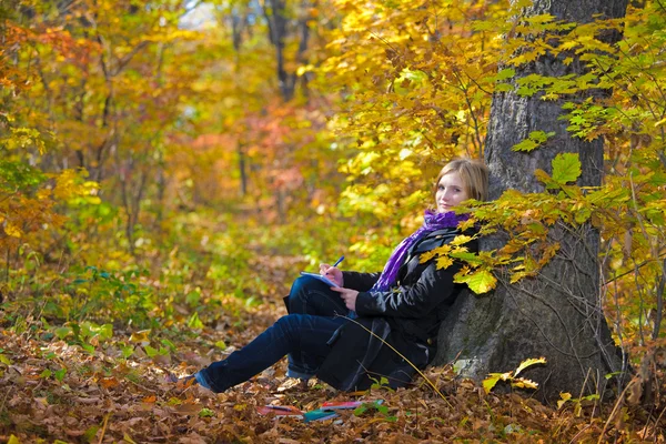 Aktivní roztomilý dívka sedící v podzimním parku — Stock fotografie