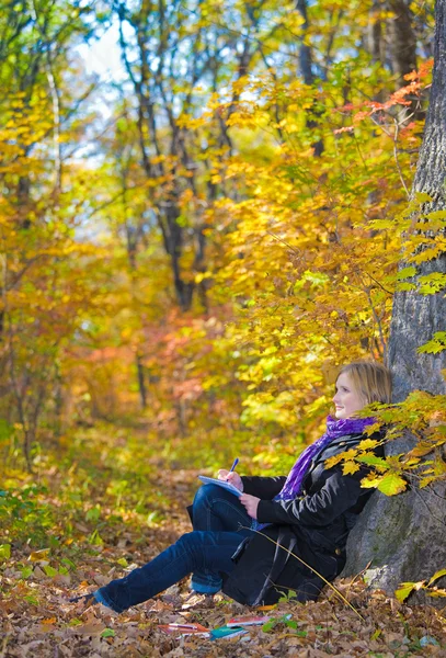 Ragazza seduta su un albero nel parco autunnale — Foto Stock