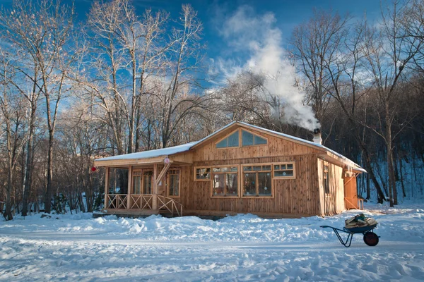 Pequeña casa de madera en un bosque nevado — Foto de Stock