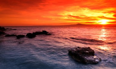 Amazing sunset over rocky seascape clipart