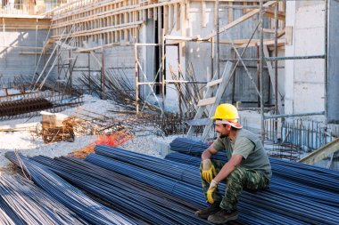 Construction worker resting on steel bars clipart