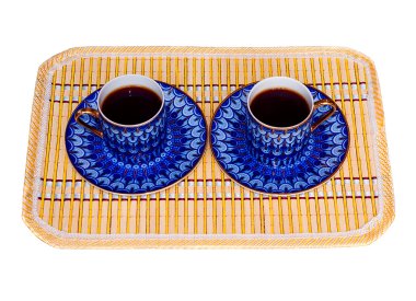 Two elegant porcelain cups with coffee at a yellow bamboo mat isolated clipart