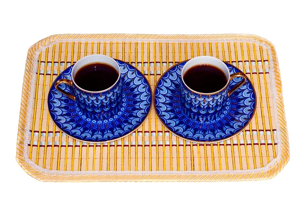 Dos elegantes tazas de porcelana con café en una alfombra de bambú amarillo aislado — Foto de Stock