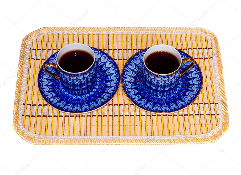 Two elegant porcelain cups with coffee at a yellow bamboo mat isolated
