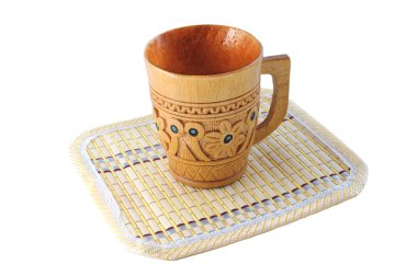 Carved wooden cup with a pattern on a bamboo mat isolated on white backgrou clipart
