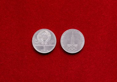 Old soviet ruble coin with symbol of 22 Olympic Game on red velvety backgr clipart