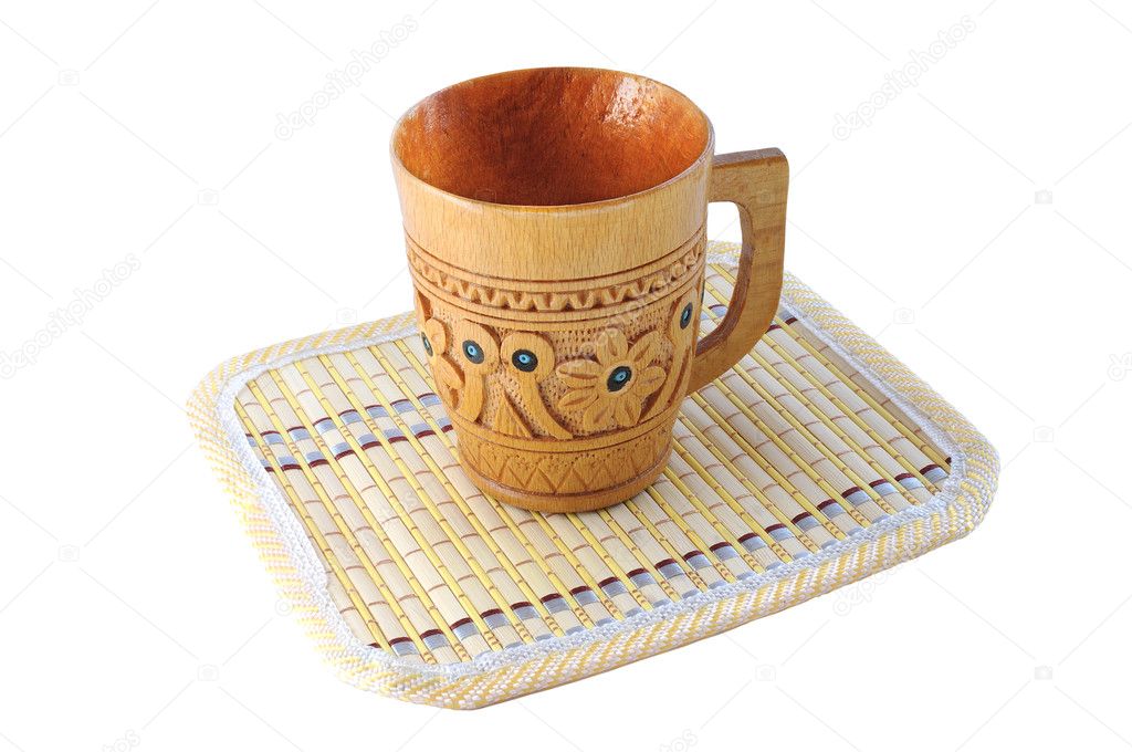Carved wooden cup with a pattern on a bamboo mat isolated on white backgrou