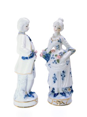 Porcelain figurines of young men and women arc turned to each other. clipart