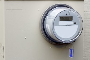 Close-up of a digital energy monitor on the exterior of a residential home. clipart