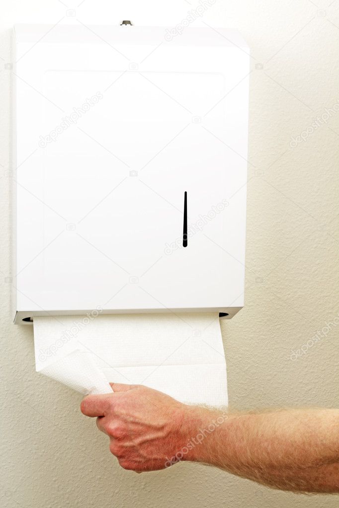 A hand is pulling down and out a white folded sheet of disposable paper to dry hands from a wall box.