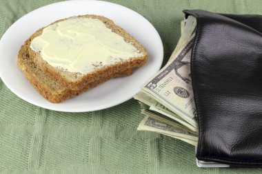 Two slices of toasted whole wheat bread on a plate with American money spilling out of a wallet. clipart