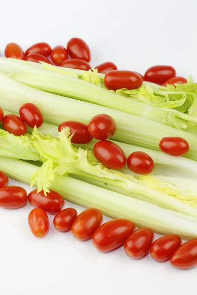 新鲜长长的绿蔬菜和小椭圆形红色水果混合白色的角度上 — 图库照片