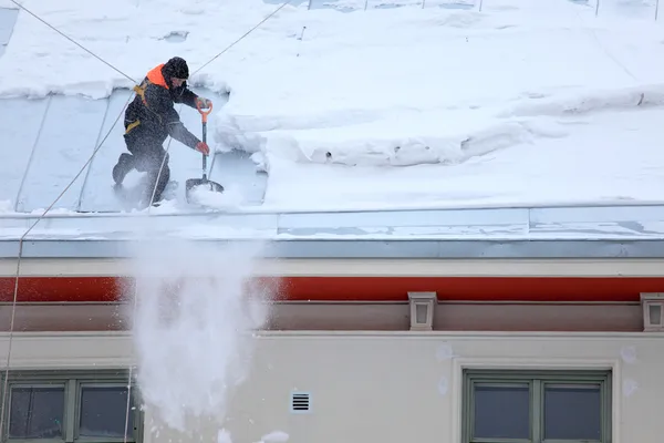 男は、雪に覆われた屋根を着氷します。 ストック写真