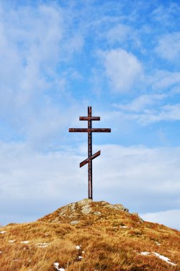 Cross against the sky on high hill clipart