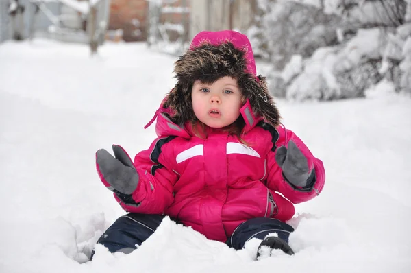 Roztomilé batole dívka sedící na sněhu — Stock fotografie