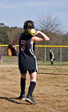 A preteen girl throwing a softball to a teammate during a game. clipart