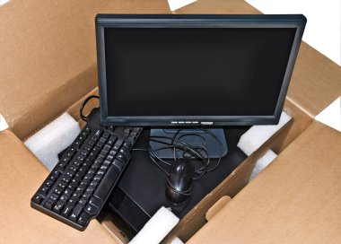 Components of a new computer system in a cardboard box. clipart