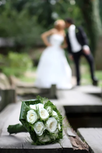 結婚式のカップルが結婚式の花束の後ろにキス — ストック写真