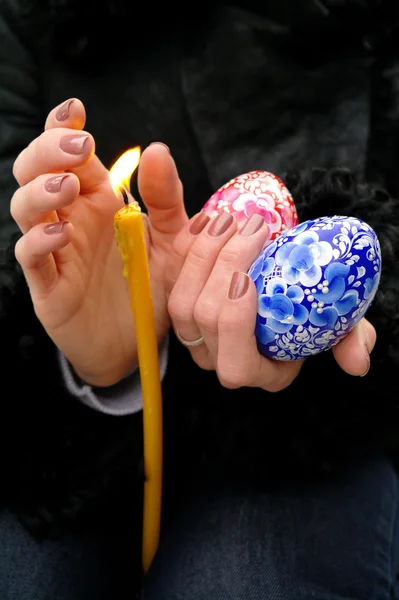 Церковные свечи и пасхальные яйца в руке девушки — стоковое фото