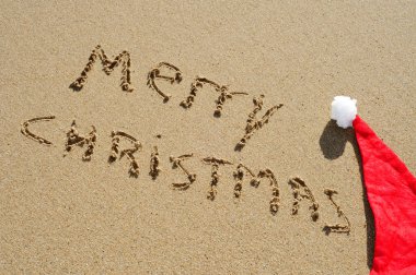 Merry christmas written in the sand and a santa had clipart