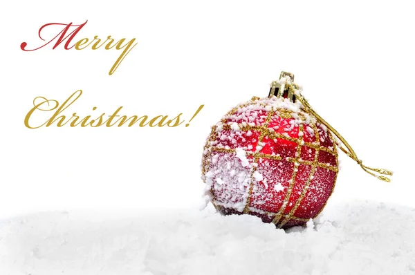 Boule de Noël rouge et dorée sur la neige et phrase joyeux Noël — Photo