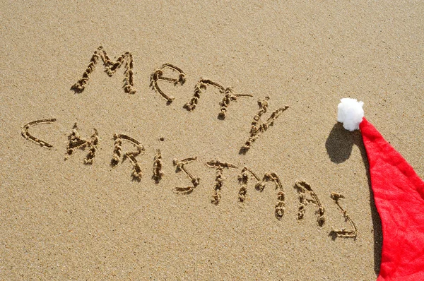 Merry christmas written in the sand and a santa had — Stock Photo, Image