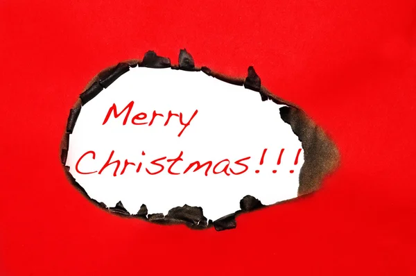 Feliz Navidad escrito en un agujero sobre un fondo de cartón rojo — Foto de Stock