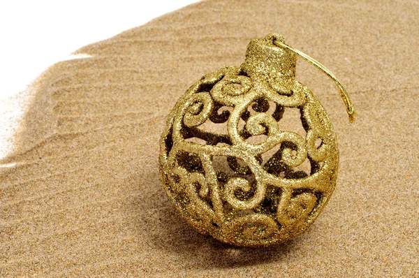 A golden christmas ball on the sand — Stockfoto