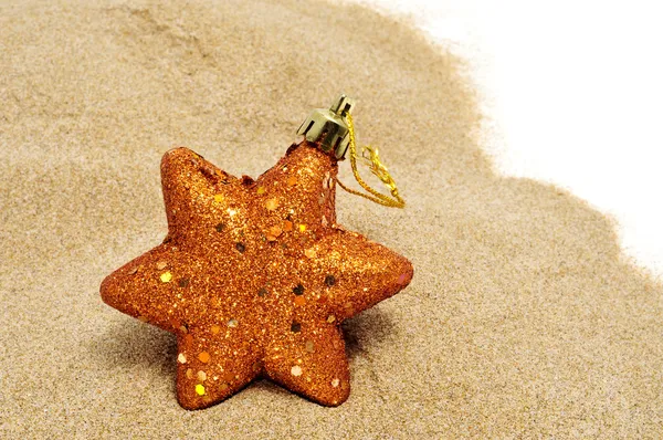 A golden christmas star on the sand — Stock Photo, Image