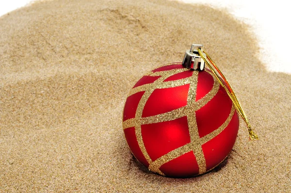 Μια κόκκινη και χρυσή σφαίρα Χριστουγέννων στην άμμο — Φωτογραφία Αρχείου