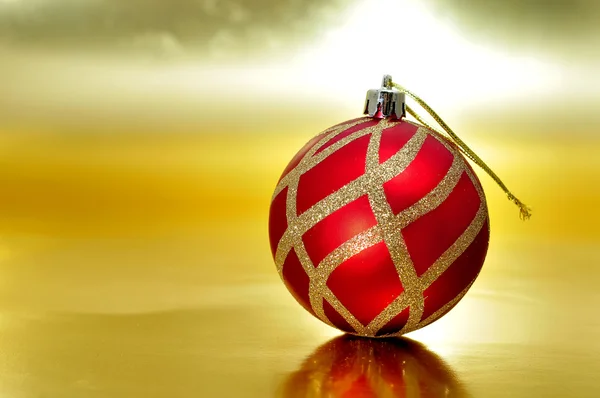 Bola de Natal vermelho e dourado em um fundo dourado — Fotografia de Stock