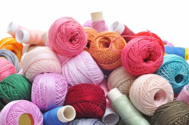 Spools and balls of yarn of many colors on a white background clipart
