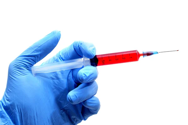 Someone wearing medical gloves holding a syringe — Stok fotoğraf
