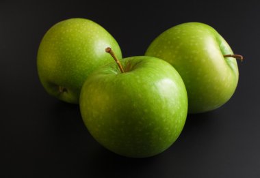 Three fresh ripe green apples close up arranged on dark background clipart