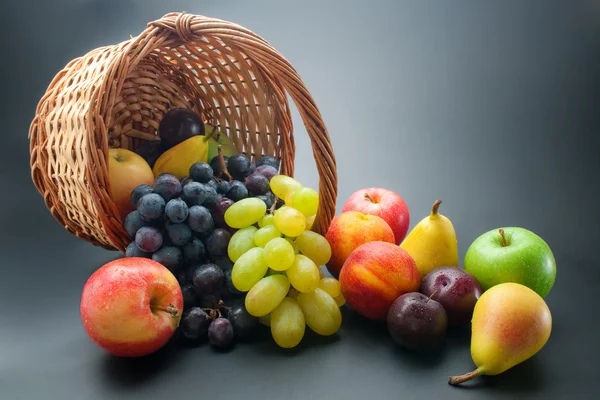 な新鮮な熟した果物 暗いグラデーション背景に枝編み細工品バスケットからの散乱 — ストック写真