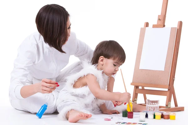Happy mom and son dressed in white painting near easel — Stock Photo, Image