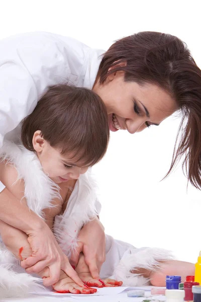 Glückliche Mutter macht mit den bemalten Händen ihres Sohnes Spuren — Stockfoto