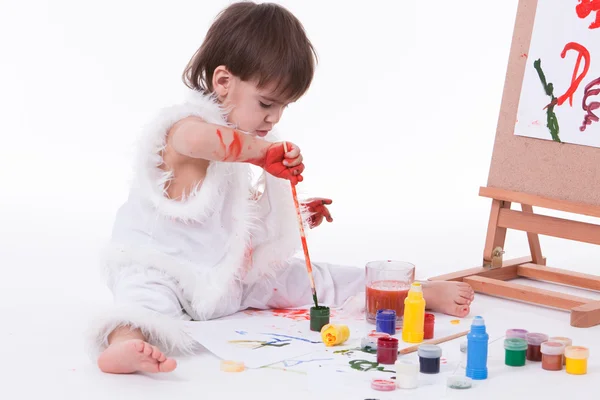 Cute little creative boy in white painting with brush — Stock Photo, Image