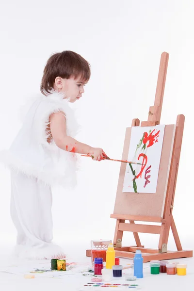 Cute little creative boy in white painting on easel — Stock Photo, Image