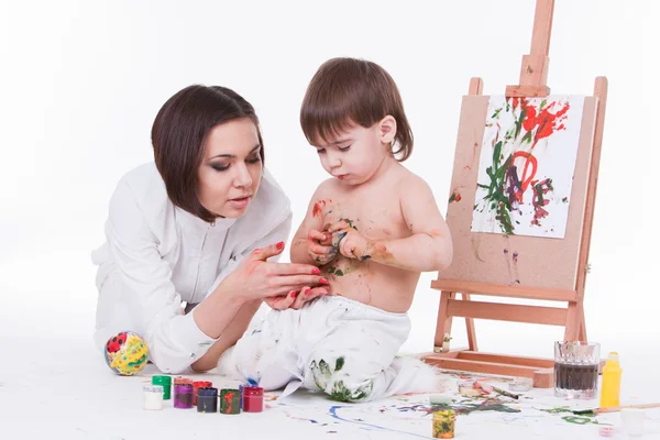 Mom helping son open colorful bottles of paints near easel — Stock Photo, Image