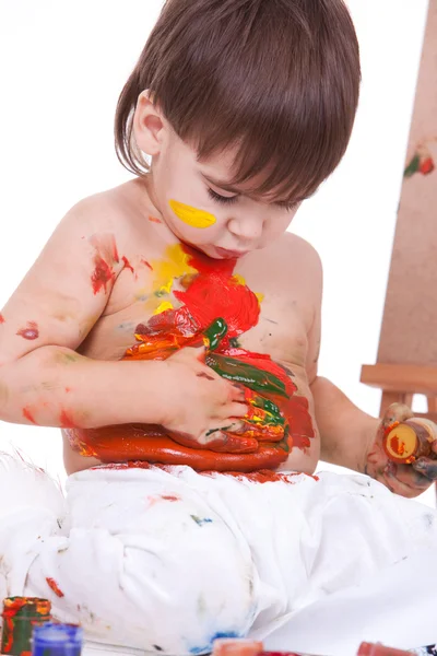 Porträt eines süßen Kindes, das mit den Händen auf dem Bauch Farben verteilt — Stockfoto